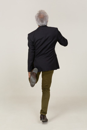 Back view of a man in a jacket standing on one leg