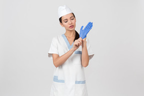 Привлекательная медсестра в медицинском халате надевает латексную перчатку