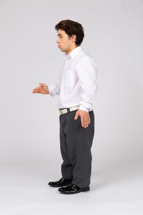 Вид сбоку на молодого человека в формальной одежде, раскинувшего руки