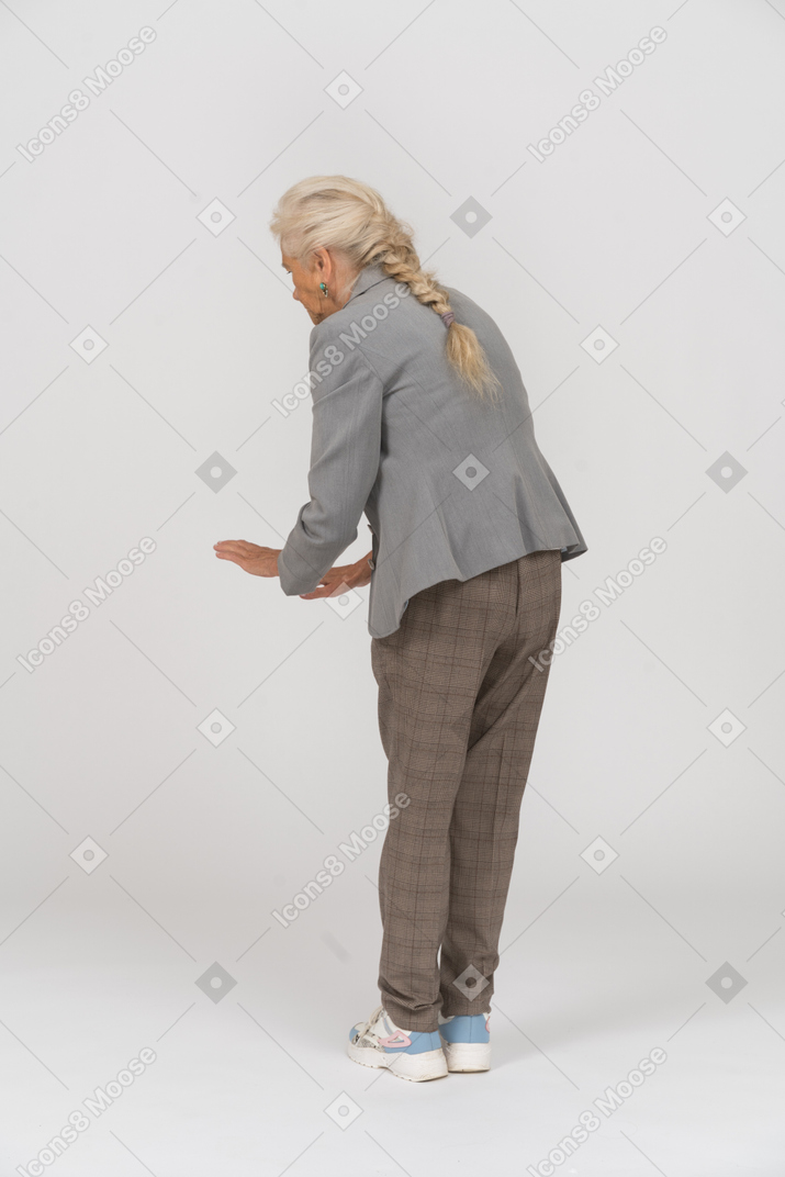 Rear view of an old lady in suit bending down