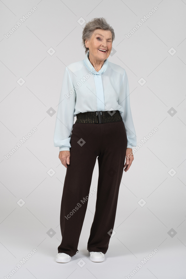 Vista frontal de una anciana sonriendo y guiñando un ojo con el ojo izquierdo