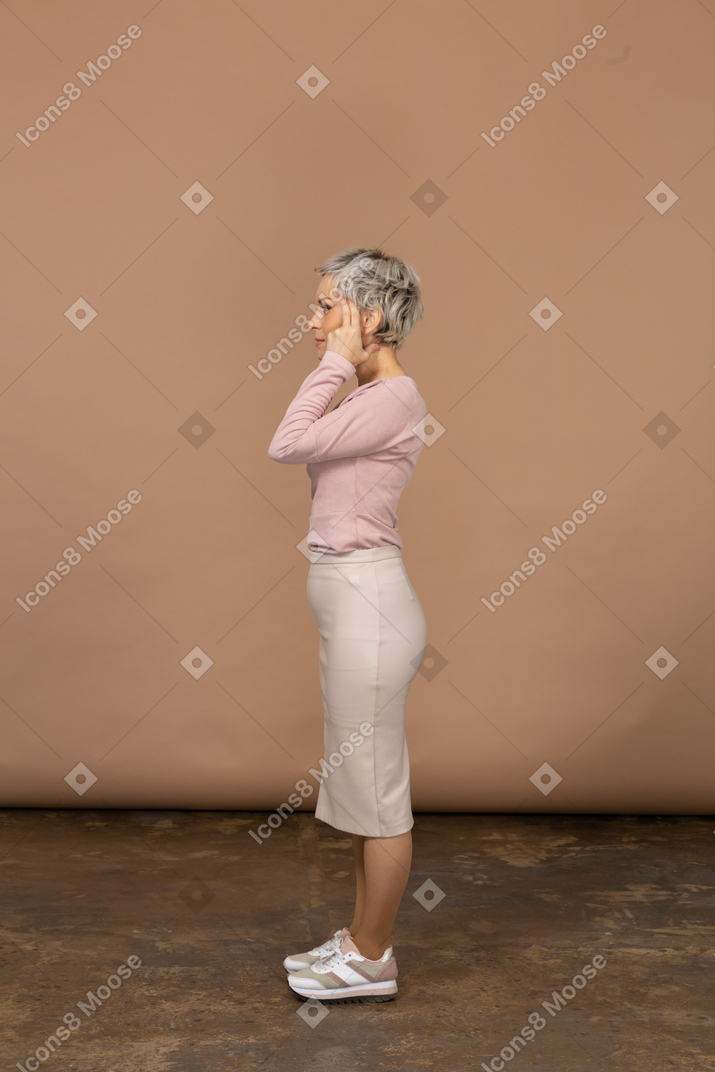 Vista lateral de una mujer en ropa casual cubriendo las orejas con las manos