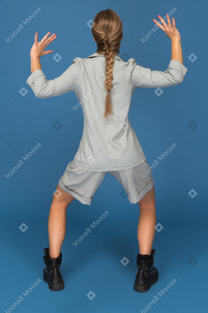 Young woman doing a half squat backwards to camera