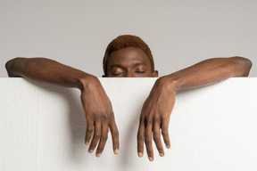 Front view of a young afro man standing behind styrofoam