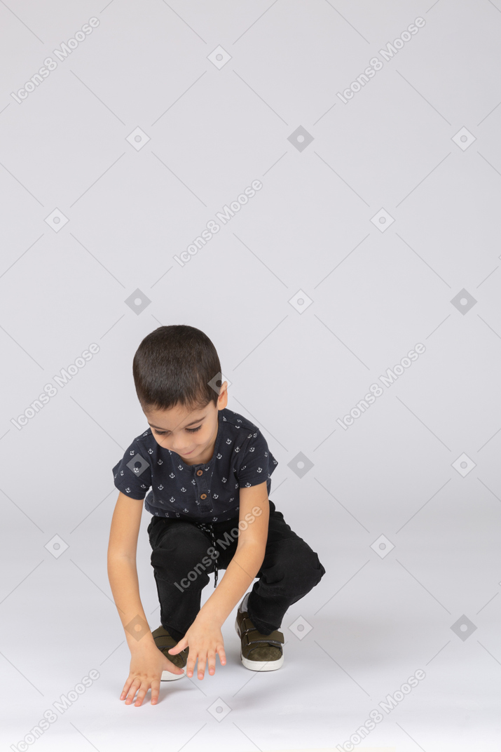 Vista frontal de um lindo menino sentado e brincando