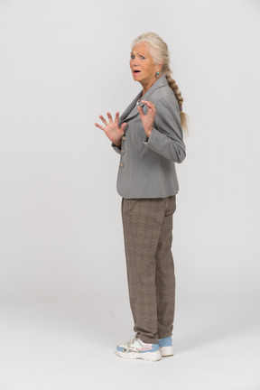 Rear view of a shocked old lady in suit gesturing