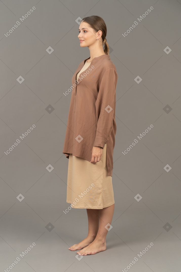Vista laterale di una giovane donna in piedi a piedi nudi e sorridente