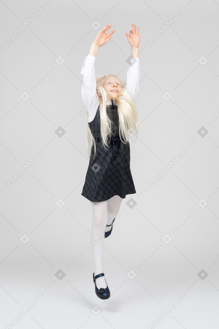 Studentessa che salta con le mani in alto