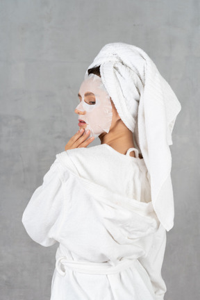 Vue arrière d'une femme en peignoir avec un masque facial sur