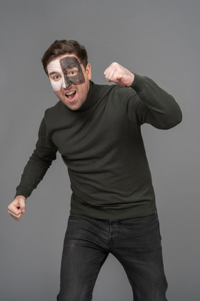 Front view of a cheerful male football fan raising hand & clenching fists