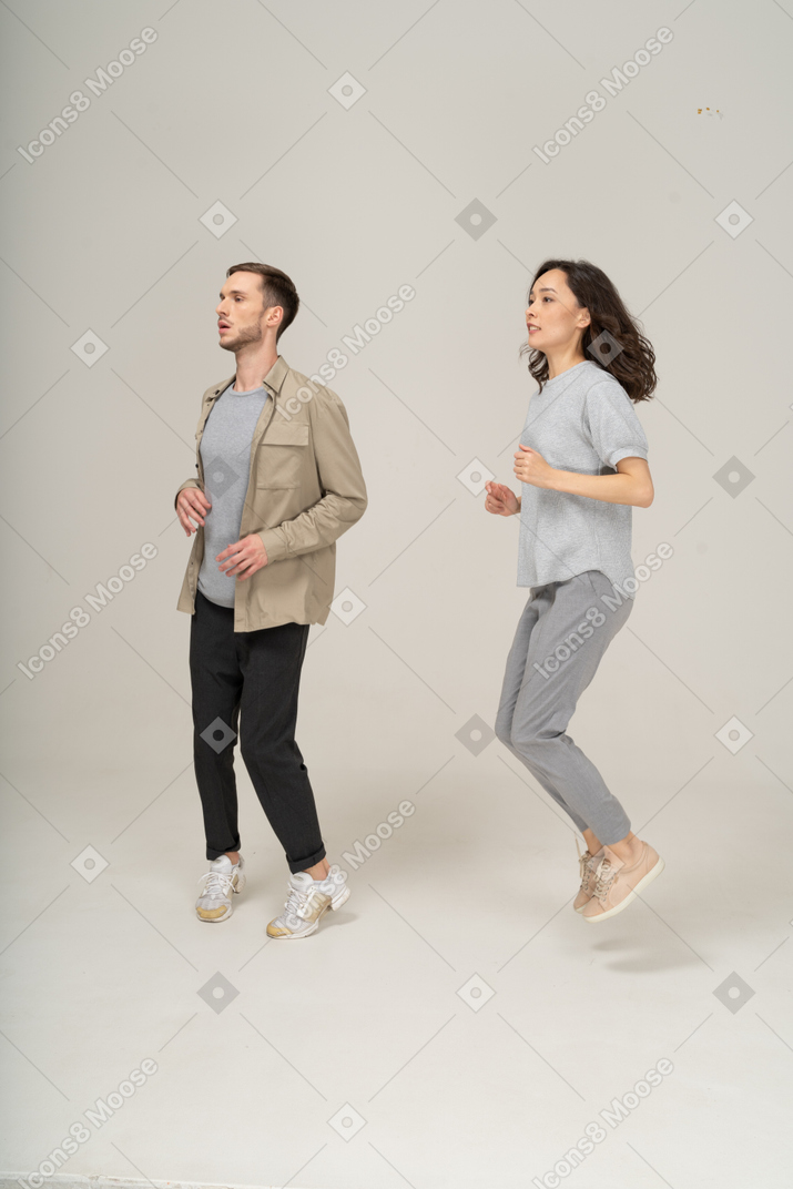 Three quarter view of young man and woman jumping