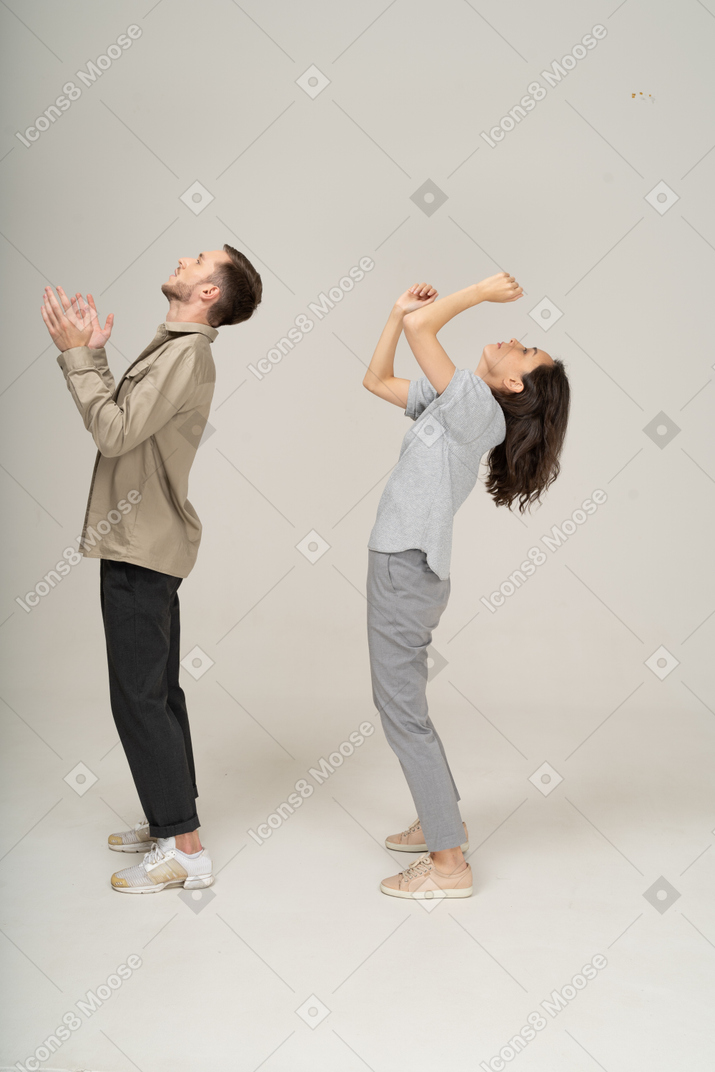 Side view of young people raising their hands