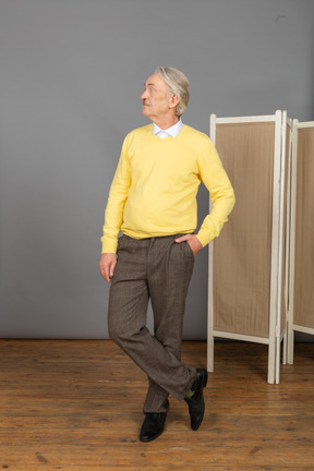Front view of an old man putting hand in pocket while looking aside