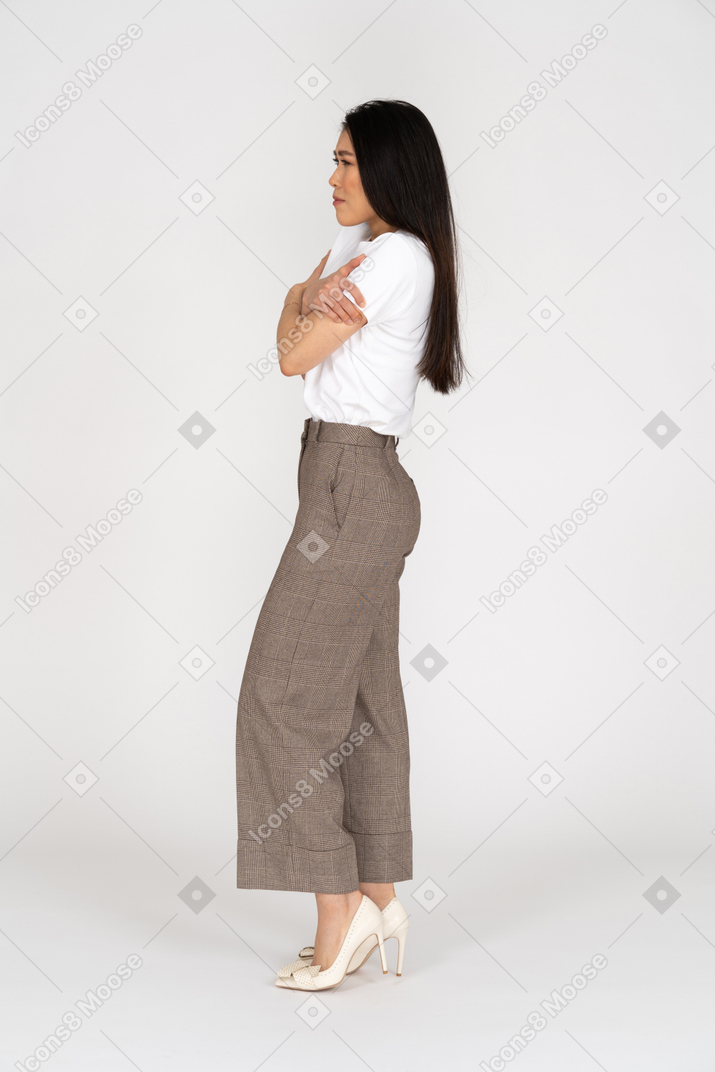 Side view of a young lady in breeches and t-shirt embracing herself