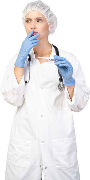 Front view of a worried young female doctor with stethoscope holding thermometer