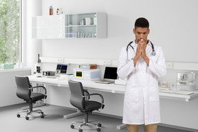 A man in a lab coat standing with folded hands in the lab