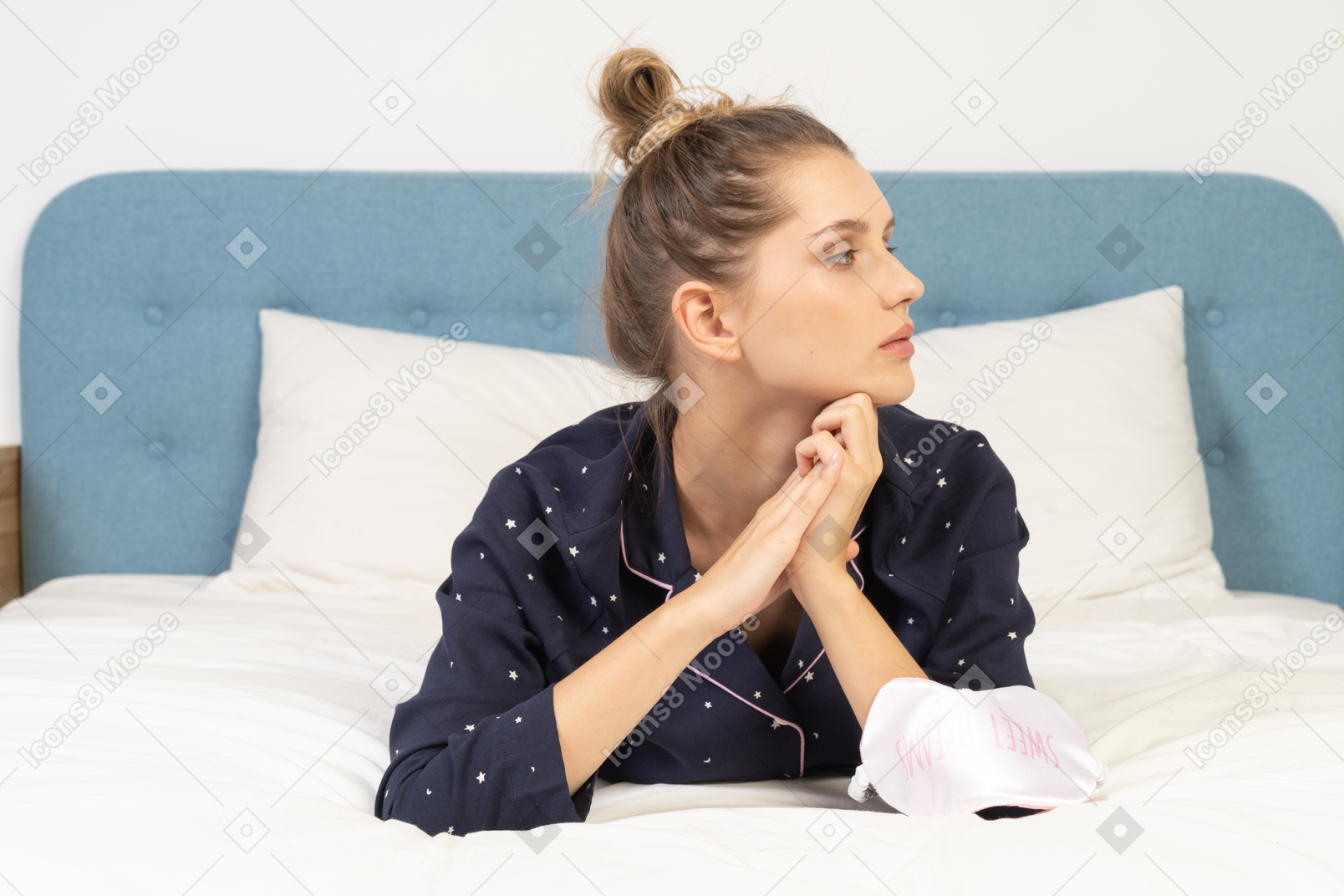Front view of a dreaming young female laying in bed and holding hands together