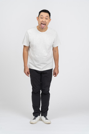 Vista frontal de um homem em roupas casuais, mostrando a língua e olhando para a câmera