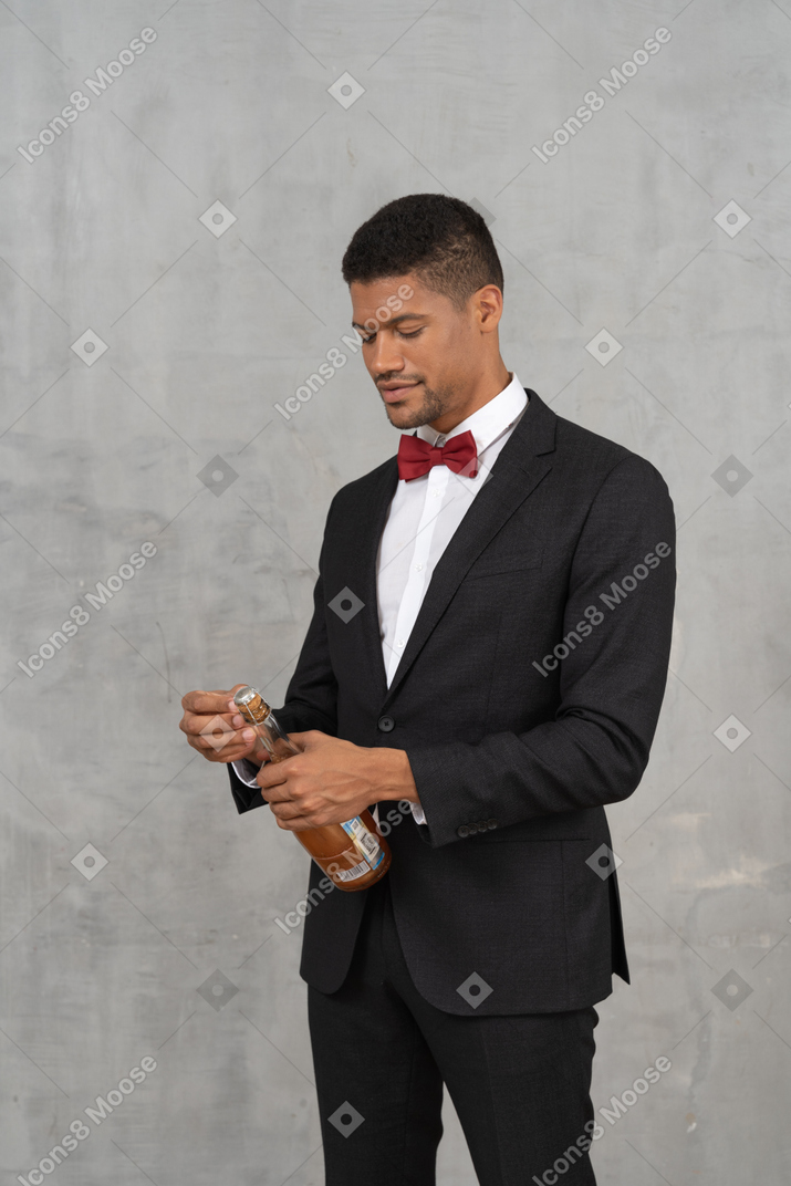 Man looking down at a champagne bottle and looking at it