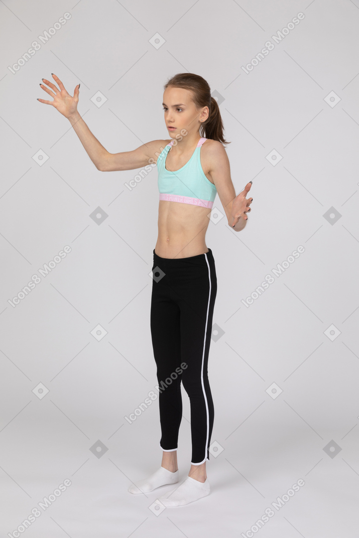 Una adolescente en ropa deportiva levantando las manos.