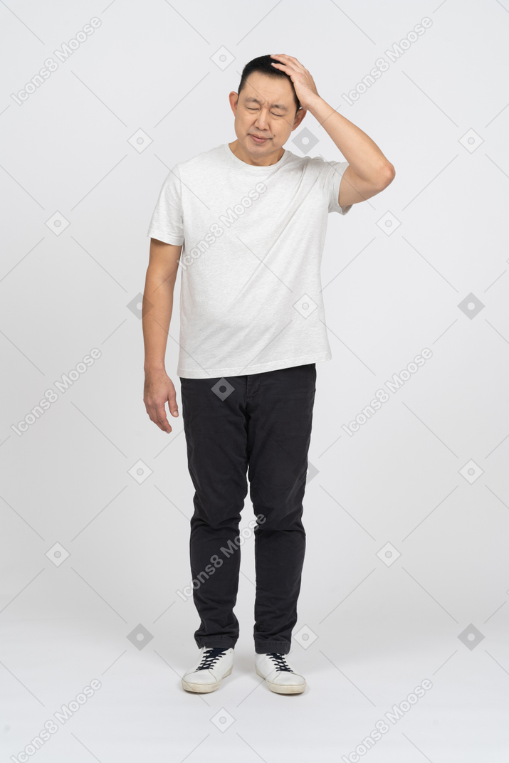 Front view of a man in casual clothes suffering from headache