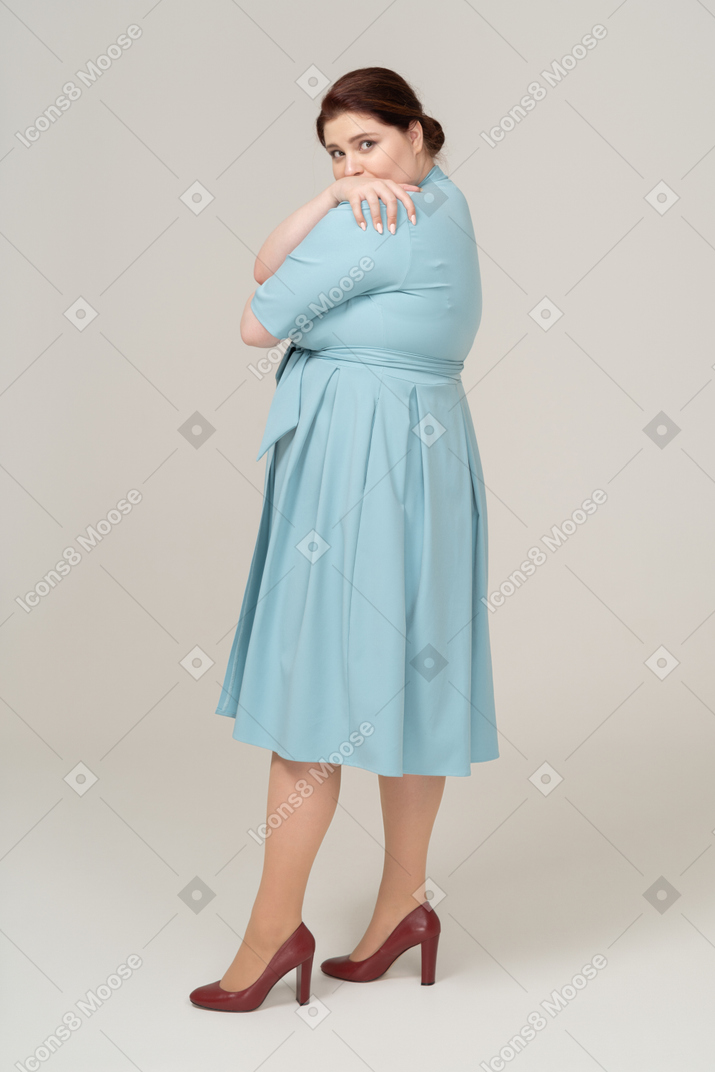 一个穿着蓝色连衣裙的女人拥抱自己的侧视图