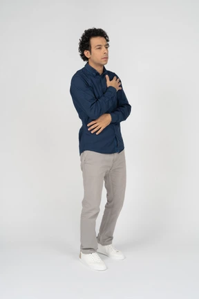 Side view of a man in casual clothes posing with hand on chest