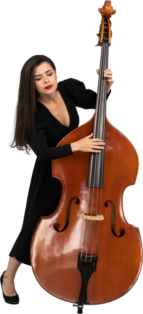 一个年轻的女人，穿着黑色的连衣裙，演奏低音提琴和往下看的前视图