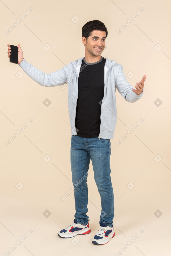 Young caucasian man presenting smartphone