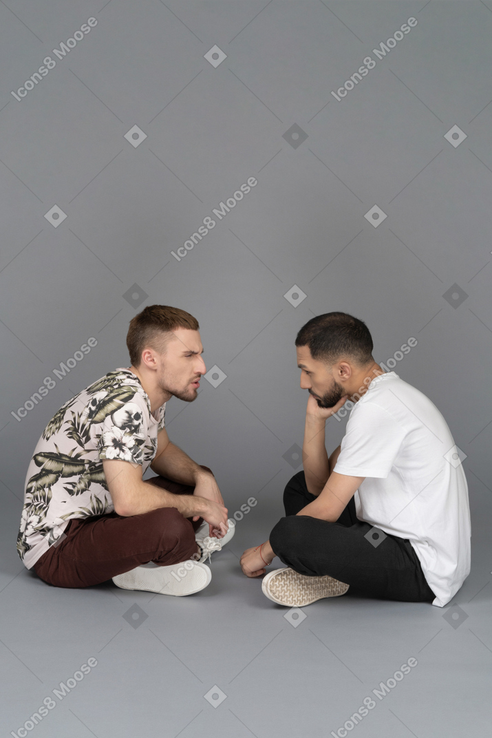Side view of two concerned young men conversing