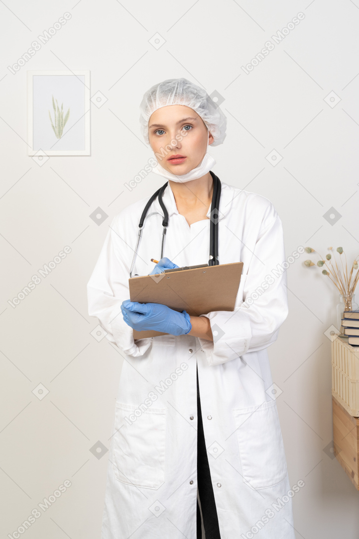 Vista frontale di una giovane dottoressa che prende appunti sul suo tablet