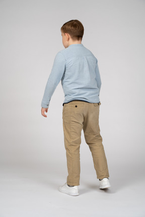 Back view of young boy in blue shirt and khaki pants