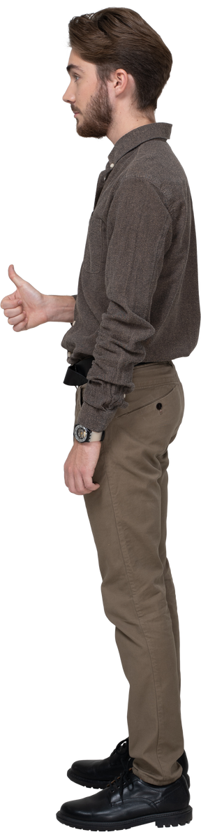 Vista lateral de un joven alegre en ropa de oficina mostrando el pulgar hacia arriba