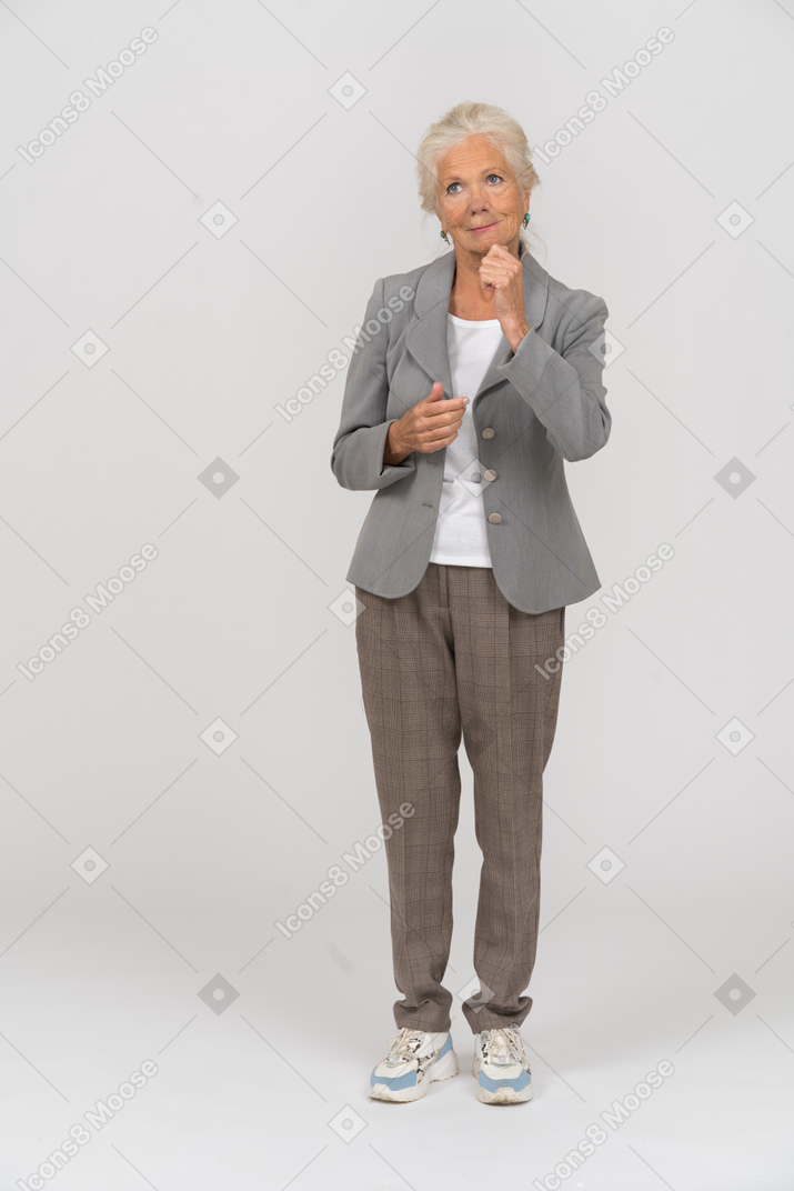 Vorderansicht einer glücklichen alten dame im anzug, die faust zeigt