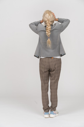 Rear view of an old lady in suit closing eyes with hands