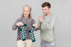 Elegant old woman giving socks as a present to a young guy