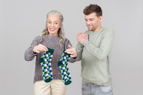 Elegante alte frau, die einem jungen kerl socken als geschenk gibt