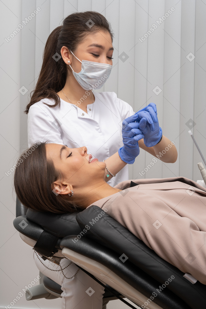 시간을 확인하는 여성 치과 의사와 아래를 내려다 보는 여성 치과 의사