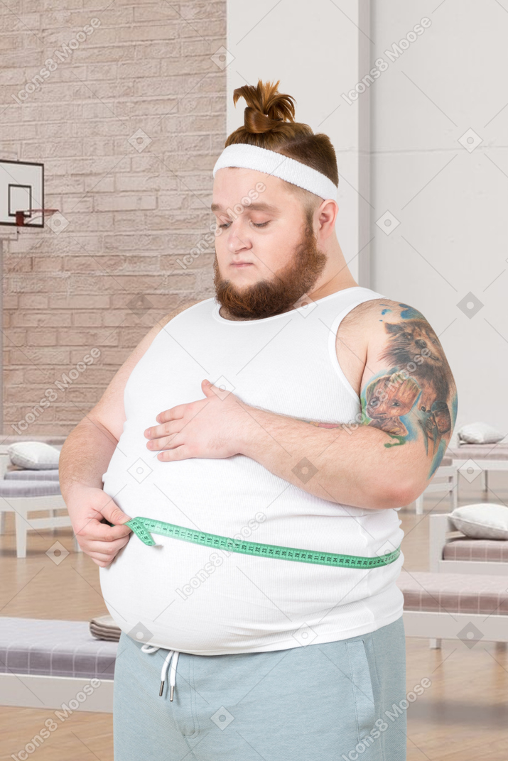 Homem ruivo completo medindo sua cintura