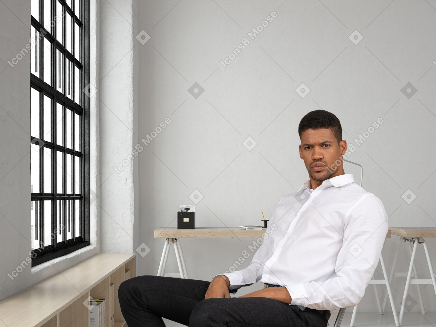 A man in a white shirt sits on a chair in his office