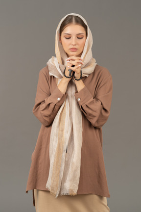 Young woman praying with rosary beads