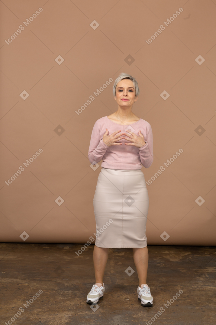 一个穿着休闲服的女人的前视图，双手放在胸前，看着相机