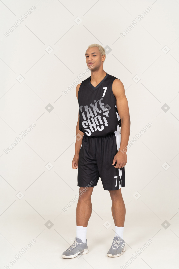 Vista de tres cuartos de un joven jugador de baloncesto masculino seguro de pie todavía