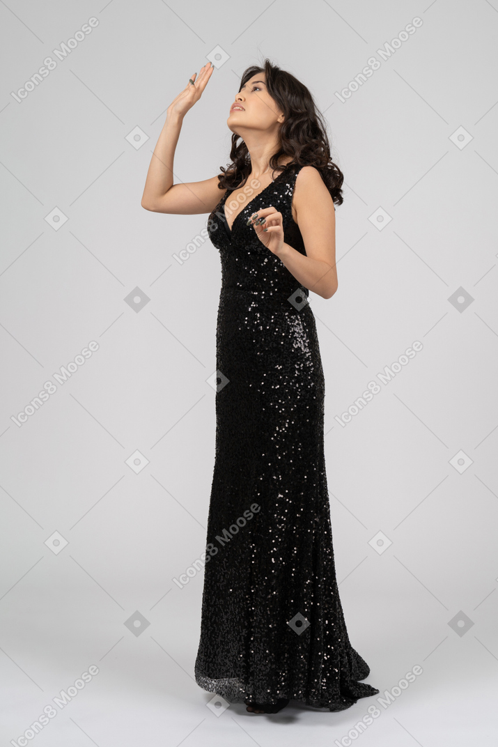 Woman in black evening dress waiving hand to somebody above her