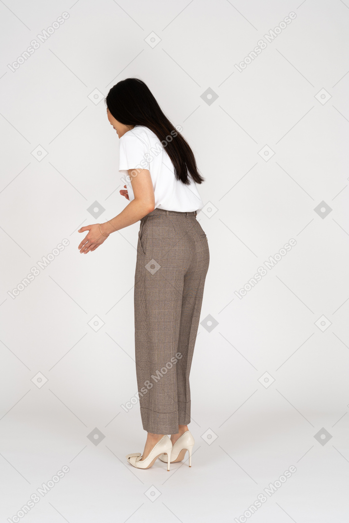 Three-quarter back view of a gesticulating young lady in breeches and t-shirt