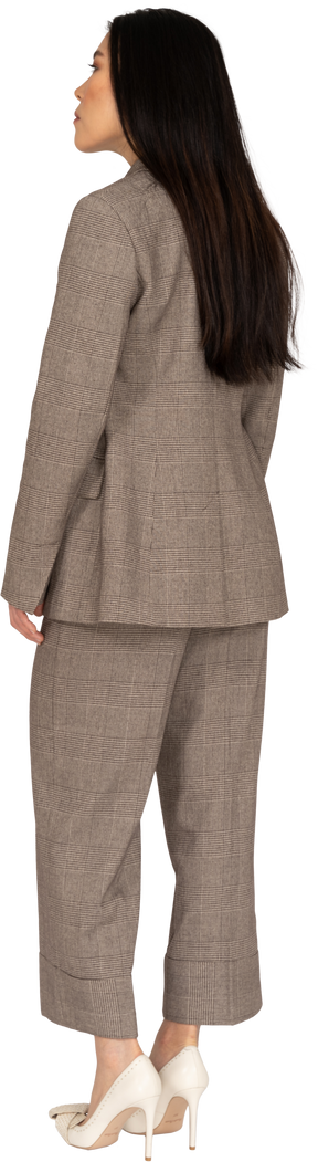 Three-quarter back view of a young lady in brown business suit leaning forward