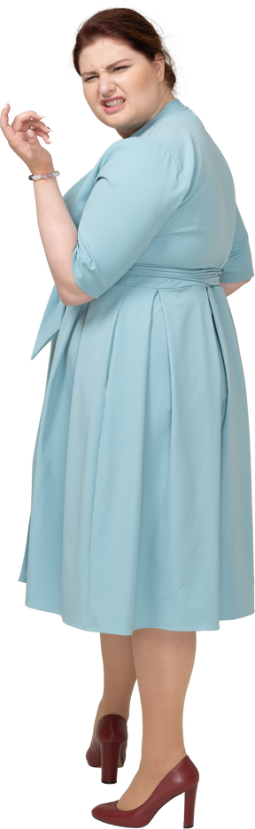Женщина в синем платье корчит рожи, вид сбоку