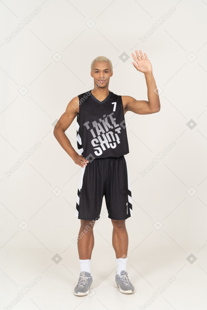 Vista frontale di un giovane giocatore di basket maschile di saluto che alza la mano