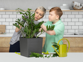 A woman and a boy are looking at a potted plant