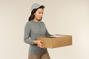 Young asian delivery girl holding boxes with folder on it